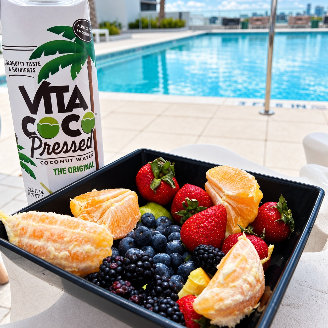 Fresh fruit and coconut water beside a rooftop pool